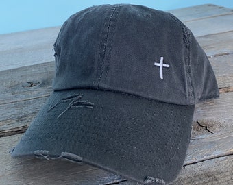May include: A black distressed baseball cap with a white embroidered cross on the front.