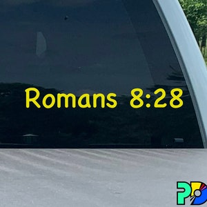 Può includere: Un adesivo in vinile giallo con il testo "Romani 8:28" su un finestrino di un'auto nera.