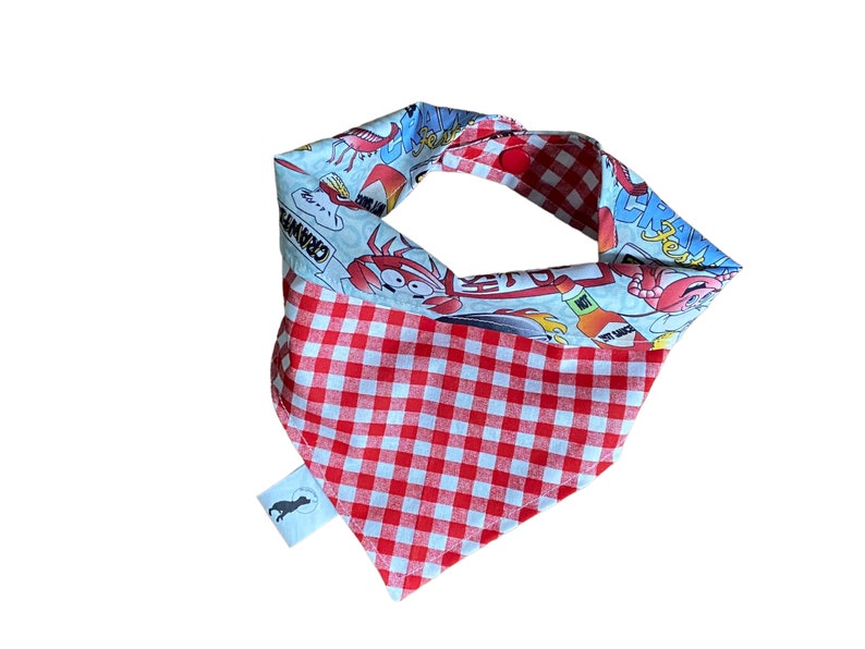 May include: Red and white checkered bandana with a blue and white print of a cartoon crab and the words "Crawfish" and "Hot Sauce".