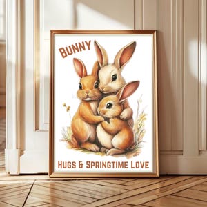Könnte beinhalten: Ein gerahmter Druck mit drei entzückenden Hasen in warmen Braun- und Cremetönen, die sich umarmen. Der Text "BUNNY" steht oben und "HUGS & SPRINGTIME LOVE" unten. Das Kunstwerk ist vor einem weißen Hintergrund.
