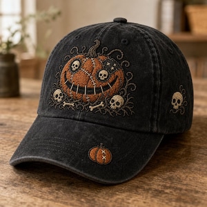 May include: A black washed-denim baseball cap featuring an embroidered orange pumpkin with stitched details and skull eyes on the front panel. Additional small skull and bone embroidery surrounds the pumpkin, with a single skull on the side and a small pumpkin on the brim.