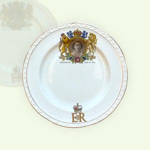 May include: White commemorative plate with a gold rim and a detailed crest featuring a portrait and the text "Coronation June 2nd 1953". The plate also has the initials "ER" and a crown.