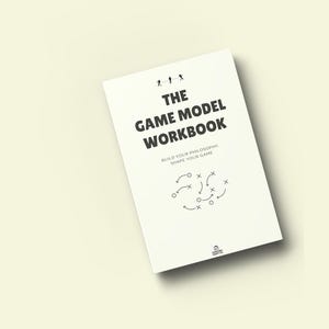 May include: A white workbook titled "The Game Model Workbook" with black text and illustrations. The cover includes the text "Build Your Philosophy, Shape Your Game." The book is angled on a light yellow background.