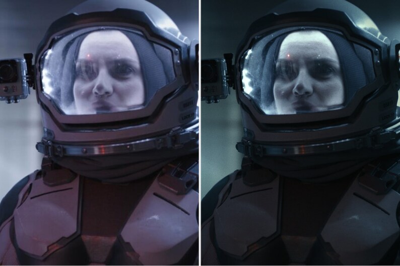 May include: A close-up of a person wearing a space suit helmet with a clear visor. The person's face is visible through the visor. The helmet is dark grey and has a black strap.