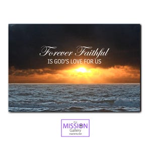 May include: A framed print featuring a seascape with a vibrant sunset over the ocean. The sky transitions from dark grey to orange and yellow. The text "Forever Faithful IS GOD'S LOVE FOR US" is displayed in white script. The Mission Gallery logo is at the bottom.