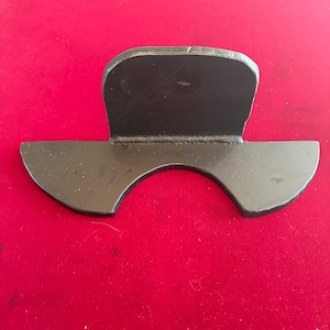 May include: A black metal bracket with a curved bottom and a straight top. The bracket is designed to support a pipe or other object.