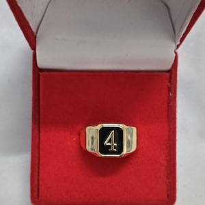 Peut inclure: Une bague en or avec un incrustation en émail noir représentant le chiffre "4" en blanc. La bague est présentée dans un écrin en velours rouge.