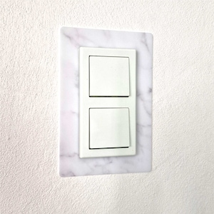 Könnte beinhalten: Ein weißer Lichtschalter mit Marmormuster. Der Schalter hat zwei Tasten.