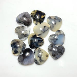 May include: A selection of heart-shaped gemstones. The stones display a variety of patterns and colours, including white, grey, and black, with distinctive, tree-like inclusions. The polished surfaces reflect light, enhancing their natural beauty.