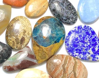 May include: A collection of polished gemstones in various shapes and colors. The stones include oval, teardrop, and irregular forms, with hues of blue, brown, orange, and gray. Some stones have unique patterns and textures.