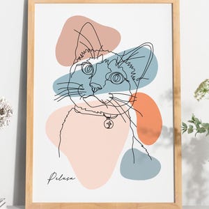 Può includere: Una stampa artistica incorniciata con un disegno a tratto minimalista del volto di un gatto con collare e ciondolo. L'opera d'arte include forme astratte in pesca, blu e arancione. Il nome del gatto, "Pelasa", è scritto sotto.