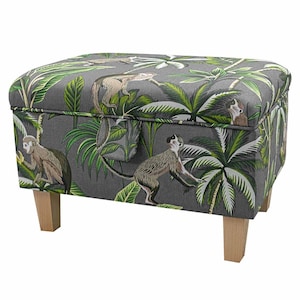 May include: A grey storage ottoman with a tropical print featuring monkeys and palm trees. The ottoman has a hinged lid and wooden legs.