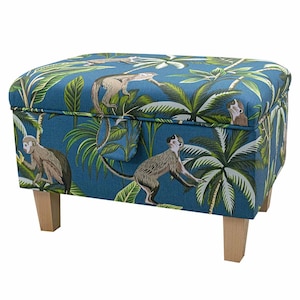 May include: A blue storage ottoman with a tropical print featuring monkeys and palm trees. The ottoman has four wooden legs.