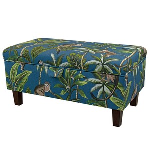 May include: A blue storage ottoman with a tropical print featuring monkeys and palm trees. The ottoman has a hinged lid and wooden legs.