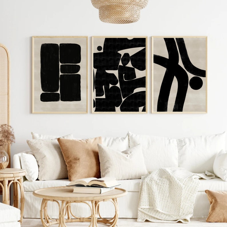 Pu&ograve; includere: Tre stampe d'arte astratta con forme geometriche in bianco e nero su sfondo beige. Le stampe sono incorniciate in una cornice in legno naturale.