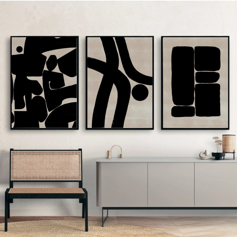 Pu&ograve; includere: Tre stampe d'arte astratta in bianco e nero con forme geometriche e linee. Le stampe sono incorniciate in nero e appese a una parete bianca sopra una cassettiera grigio chiaro.