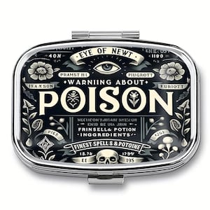 May include: A silver pill box with a black and white design. The design includes the words "Eye of Newt" and "Warning About Poison". The box also features floral and skull illustrations.