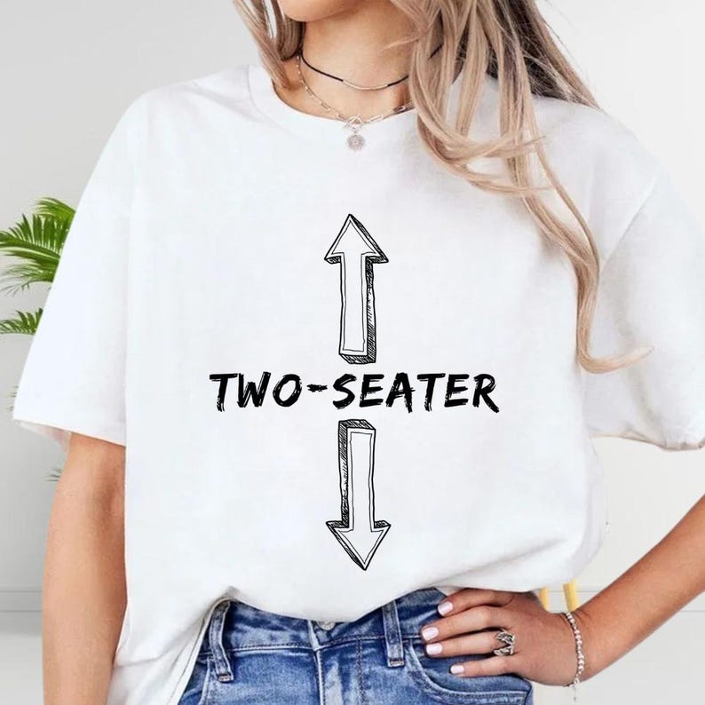 A woman wearing a white t-shirt with a graphic design and text printed on it.