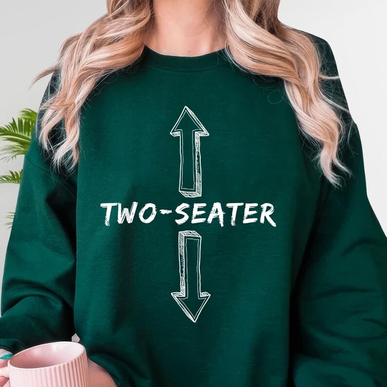A person wearing a green sweatshirt with the text "TWO-SEATER" printed on it.