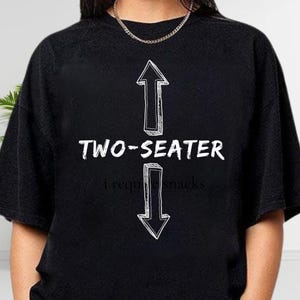 A black t-shirt with a graphic design featuring two arrows pointing upwards and the text "TWO-SEATER" below them.