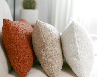 Krämfärgade, beige örngott i bouclé. Mjuka kuddar till soffan. Ländryggskudde. Mjuk texturerad kudde. Dammigt terrakottamönster.