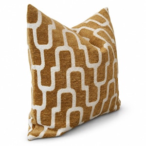 Peut inclure: Un coussin carré en tissu texturé jaune moutarde avec un motif géométrique blanc répétitif composé de formes d'arches entrelacées. Le coussin présente un aspect doux et moelleux avec un tissage uniforme sur toute la surface visible.