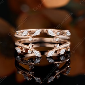 May include: Two delicate rose gold rings with a vine design and marquise-shaped diamonds. The rings are stacked on top of each other.