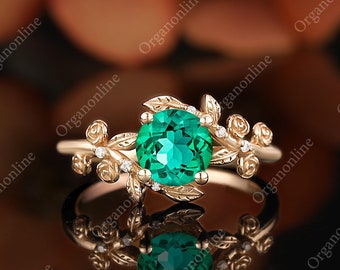 May include: A gold ring with a green gemstone surrounded by delicate floral details. The ring features a cluster of leaves and small white gemstones.