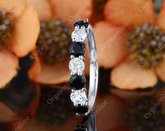 May include: A silver band ring with alternating black and white round gemstones. The ring is set against a background of orange flowers.