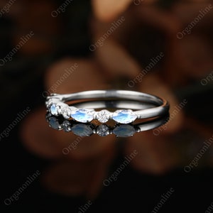 May include: A delicate silver band with a row of marquise-shaped moonstone and diamond accents.