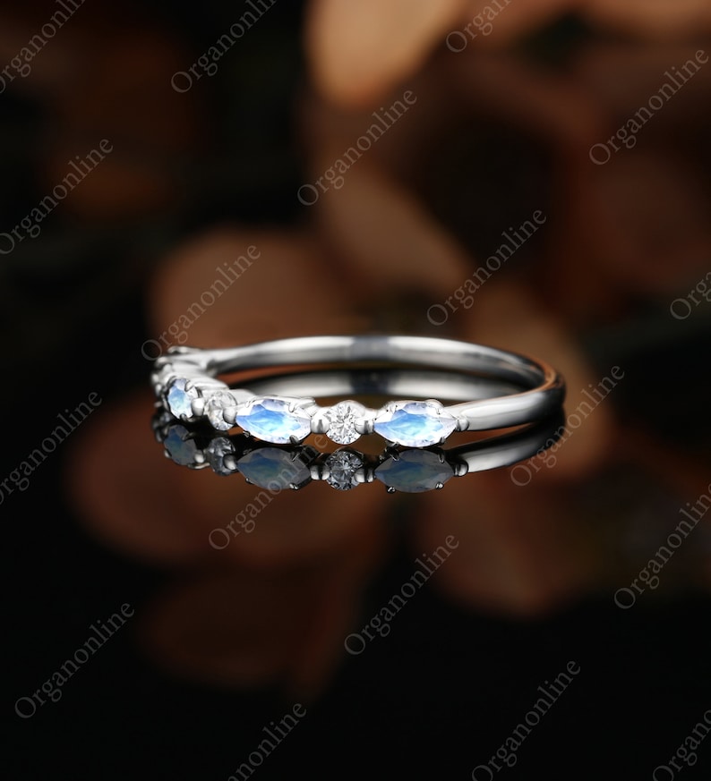 May include: A delicate silver band with a row of marquise-shaped moonstone and diamond accents.