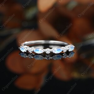 May include: A delicate silver band with a row of oval-shaped moonstone and diamond accents.