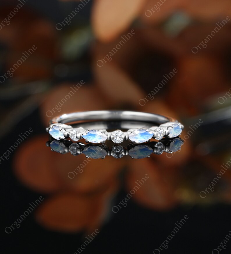 May include: A delicate silver band with a row of oval-shaped moonstone and diamond accents.