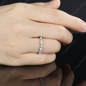 May include: A delicate silver band ring with a row of oval-shaped moonstone gemstones.