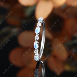 May include: A delicate silver band with a row of marquise-shaped moonstone and diamond accents.