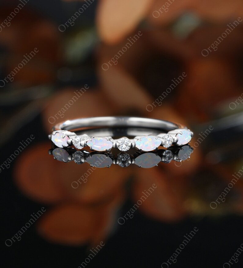 May include: A delicate silver band ring with a row of oval-shaped white opals and small round clear diamonds.