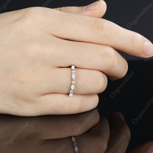 May include: A delicate silver band ring with a row of oval-shaped white opals.