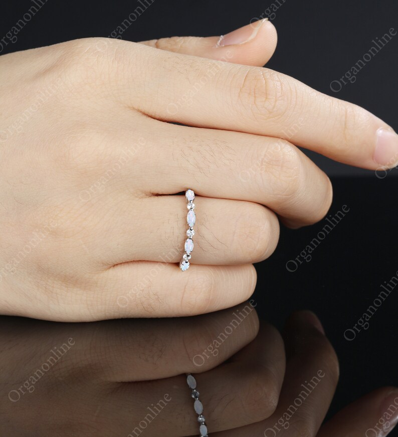 May include: A delicate silver band ring with a row of oval-shaped white opals.