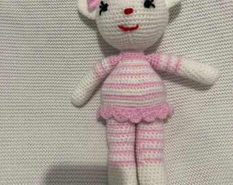 May include: A white crocheted stuffed animal with pink stripes and a pink bow. The animal has a pink nose and black eyes.