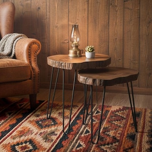 May include: A rustic living room setting with a brown leather armchair and a patterned rug. Two wooden side tables with black hairpin legs and a vintage lamp create a warm atmosphere. A small plant sits on the table. The room has wooden paneling.