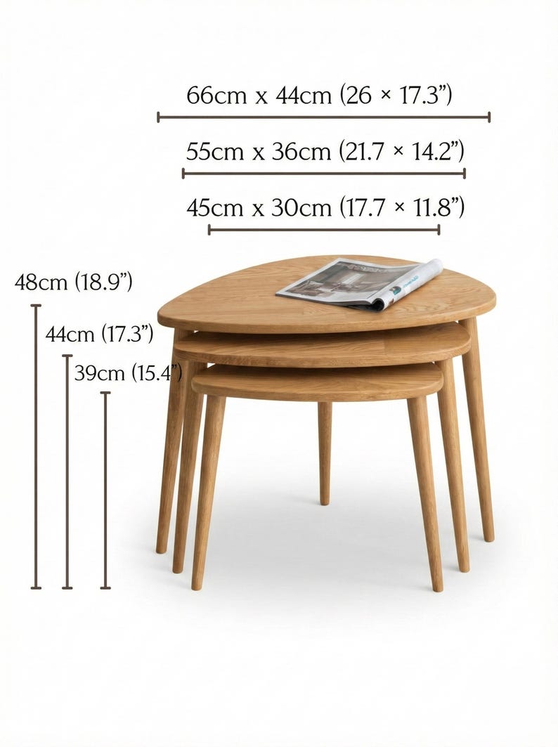 Product dimension display of a handcrafted solid wood nesting table set featuring three organically shaped tables with smooth rounded edges and tapered legs. The image shows size variations with labeled measurements in both centimeters and inches, highlighting width and height differences for each piece. Natural oak grain and warm tones are visible, while the stacked arrangement emphasizes practical nesting functionality and space-saving design.