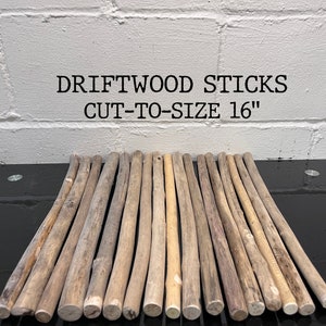 May include: A collection of driftwood sticks, cut to 16 inches in length. The natural wood pieces vary in color from light tan to grey, with visible grain and texture. The text "DRIFTWOOD STICKS CUT-TO-SIZE 16" is displayed above the sticks.