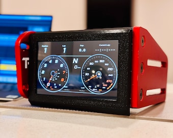 May include: A black and red racing data display with a digital screen showing the lap number, gap, and current lap time. The screen also displays two gauges, one for RPM and one for speed. The display is mounted on a red metal bracket.