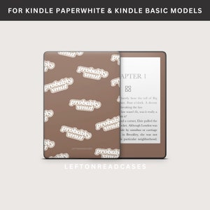May include: A brown Kindle Paperwhite and Kindle Basic model case with the words "probably smut" in a repeating pattern. The case is open, revealing the screen with text. The text "FOR KINDLE PAPERWHITE & KINDLE BASIC MODELS" is at the top.