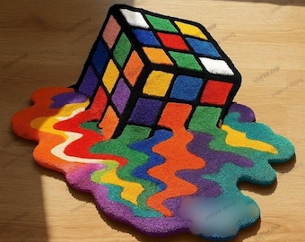 Puede incluir: Una colorida alfombra abstracta con un diseño de Cubo de Rubik en 3D. El cubo está representado en colores clásicos, con un contorno negro. El diseño parece derretirse en un charco de colores del arcoíris. La alfombra está sobre un suelo de madera.