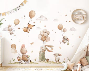Op de afbeelding: Een set muurstickers met schattige dierillustraties, waaronder konijnen, een vos en een muis. De stickers zijn in een speelse stijl met bruine, beige en witte kleuren. De dieren houden ballonnen vast en vliegen door de lucht.