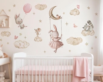 May include: A set of nursery wall decals featuring a bunny rabbit swinging on a crescent moon, a bunny rabbit holding a balloon, a mouse on a cloud, a raccoon sleeping on a cloud, and stars and butterflies. The decals are in shades of pink, brown, and gold.