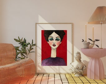 May include: A framed art print featuring a stylized portrait of a woman with dark hair, teal eyeshadow, and red lips against a red background. The woman is wearing a purple top. The artwork is displayed in a room with a pink side table and a woven chair.