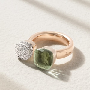 May include: A white ceramic mug with a black handle and the text "But First, Coffee" in a bold, black font. The mug is set against a blurred background, suggesting a cozy setting.