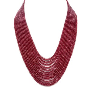 May include: A multi-strand necklace made of deep red ruby beads. The necklace is made of many strands of beads, creating a layered effect.